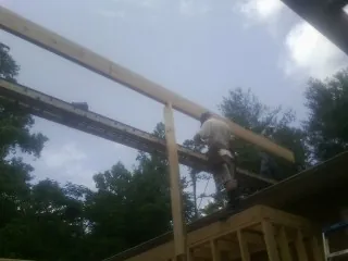 Carpenter setting a ridge beam over a new addition frame — Ice Dam Removal by Roofing Brothers in Yachats