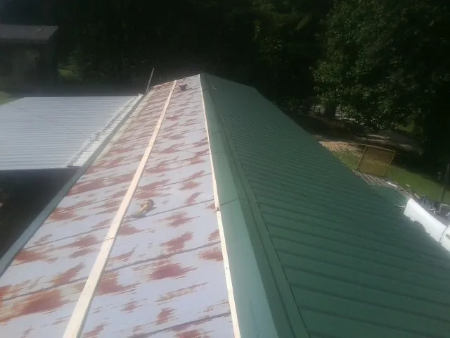 Old rusted panels beside newly installed green metal roofing — Wind Damage Roof Repair by Roofing Brothers in Yachats