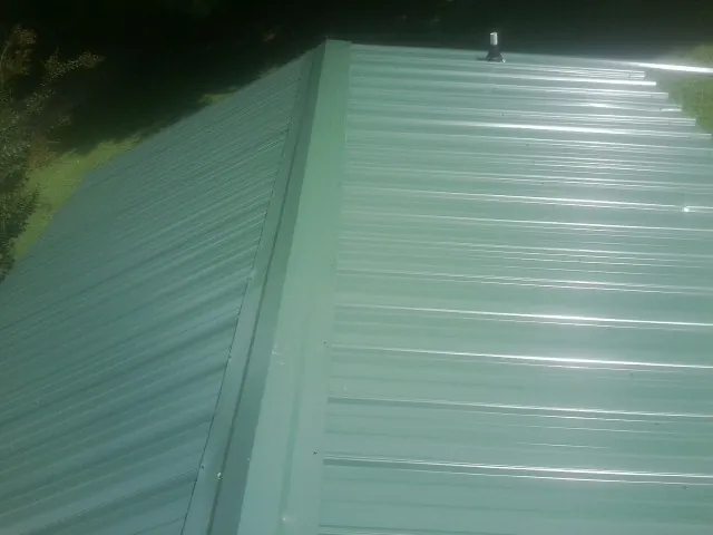 New green metal panels meeting at the ridge of a roof — Flat Roof Repair work by our crew in Yachats