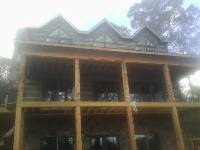 Dormers and porch framing on a large log home under construction — Roof Coating work by our crew in Yachats