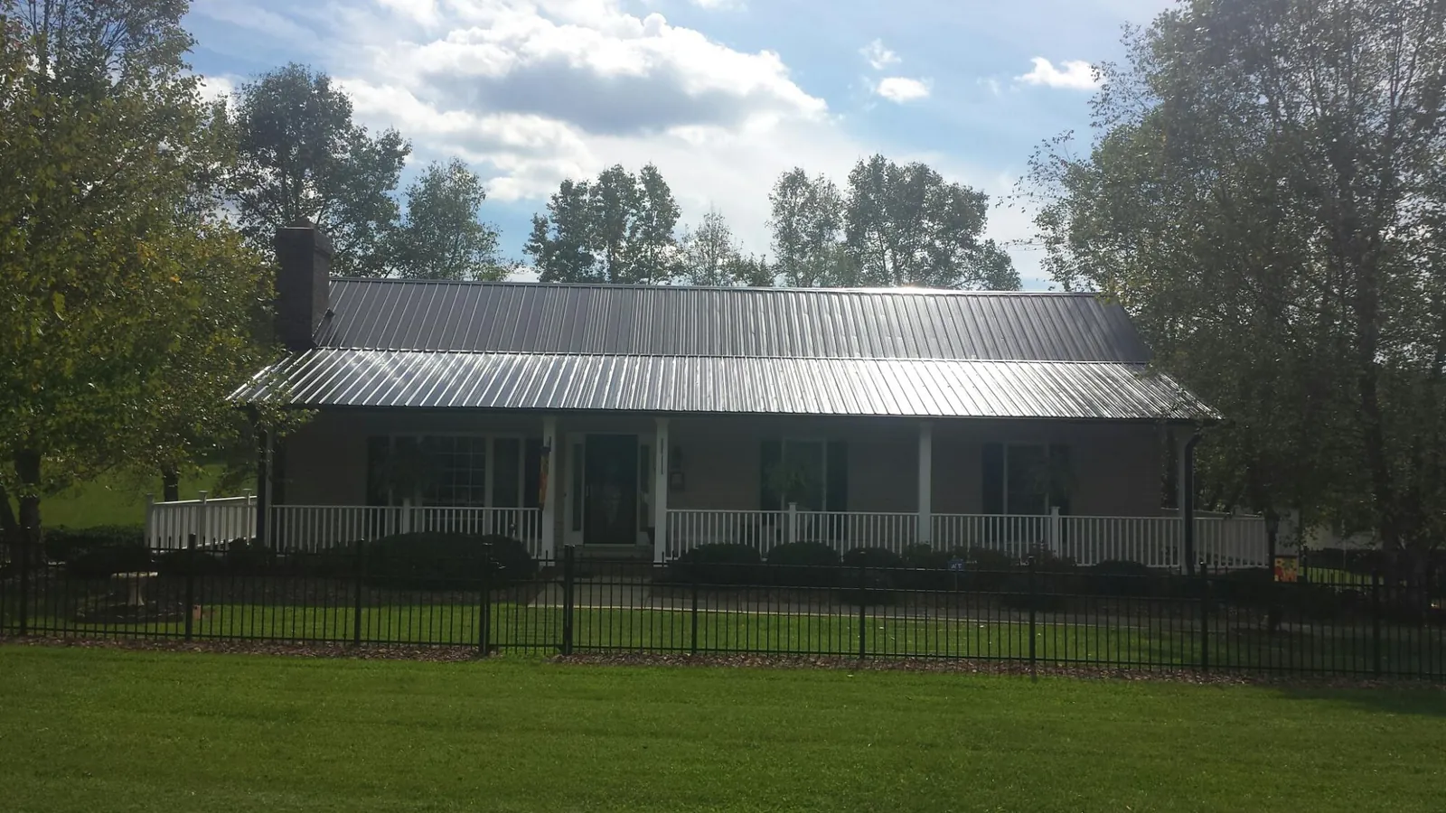 Gray metal roof on a brick ranch with a full width front porch — Gutter Guard Installation work by our crew in Yachats