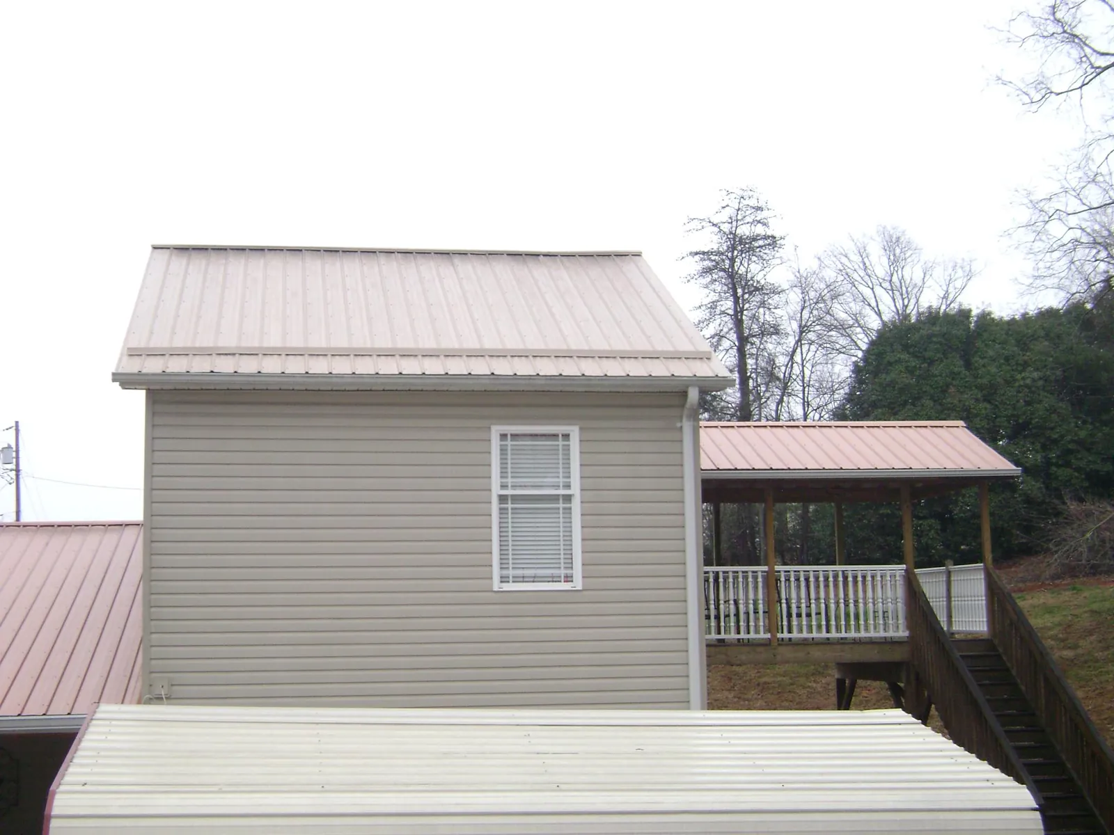 Tan metal roofs on a two story addition and attached porch, from a Roof Replacement job in Yachats