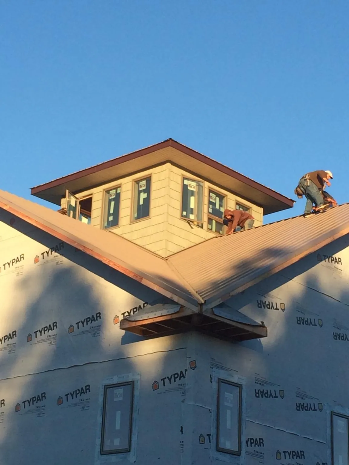 Roofers working around a rooftop cupola on a new metal roof at sunset — Roof Waterproofing in Yachats by Roofing Brothers